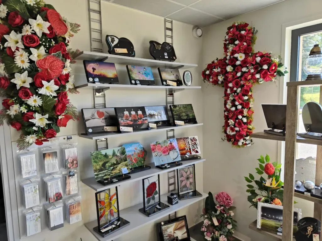 Rayonnage de plaques funéraires illustrées et compositions florales dont une croix