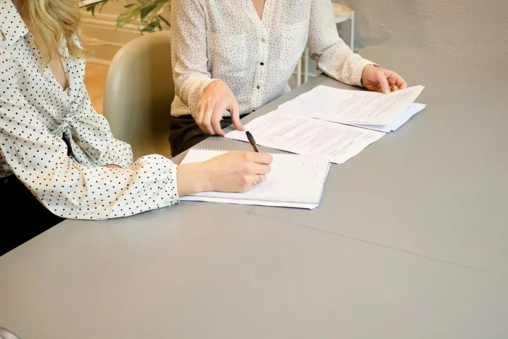 Deux femmes travaillant sur des documents administratifs et prenant des notes autour d'une table